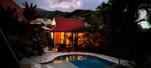 une piscine en face d'une maison avec un toit rouge dans l'établissement Fare Cocoon, à Punaauia