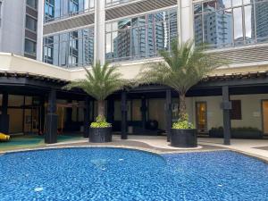 a swimming pool in front of a building with palm trees at Penthouse Perfection in Manila
