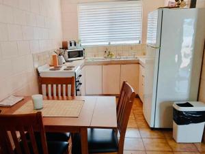 BoulderKalgoorlie, Unit 3, Paddy's Golden Patch的厨房里有一张桌子和一台白色冰箱