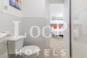 a white bathroom with a toilet and a bedroom at LooP Las Ventas in Madrid