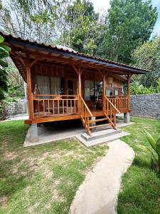 uma grande cabana de madeira com um alpendre num quintal em La pipa Uluwatu em Uluwatu