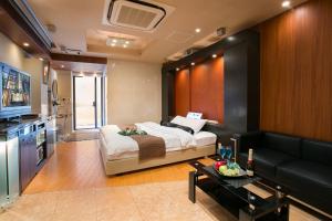 een woonkamer met een bed en een bank bij Hotel AXIS -アクシス- in Osaka