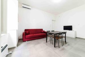 ein Wohnzimmer mit einem roten Sofa und einem Tisch in der Unterkunft [Incantevole Bilocale] Wi-Fi + Netflix in Salerno