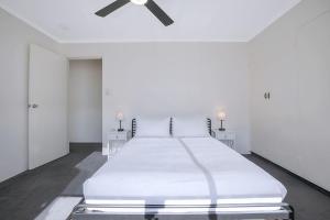 a white bedroom with a bed and a ceiling fan at The Hillside at Hamilton - A Fresh Riverfront Abode in Brisbane