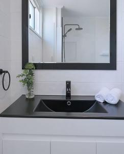 a sink in a bathroom with a mirror and towels at The Hillside at Hamilton - A Fresh Riverfront Abode in Brisbane