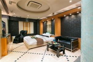 een slaapkamer met een bed, een bank en een tafel bij Hotel AXIS -アクシス- in Osaka