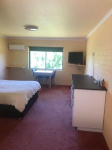 a hotel room with a bed and a desk and a table at Colonial Inn Guest Rooms in Yackandandah