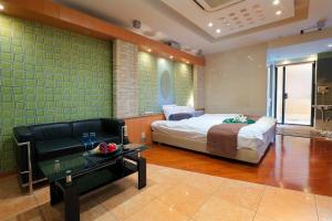a bedroom with a bed and a couch and a table at Hotel AXIS -アクシス- in Osaka