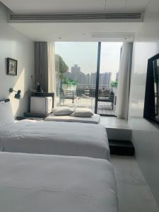 two beds in a room with a large window at Shanghai Autoongo Bund Hotel in Shanghai