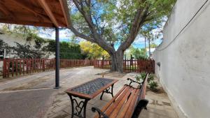 una mesa de picnic y un banco en una acera con un árbol en El Patio del Aromo en 