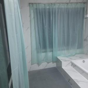 a bathroom with a green shower curtain and a sink at Mohor Retreat in Alibag