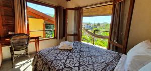 a bedroom with a bed and a desk and a window at Casa Bon Voyage - Guesthouse in Paraty