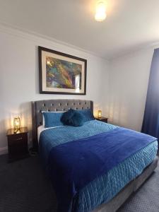 a bedroom with a bed with a blue comforter at Art Hotel on York in Launceston