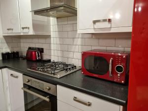 a red microwave sitting on a counter in a kitchen at C'S LUXURIOUS Flat in Barking