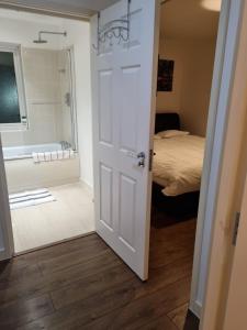 a door leading to a bathroom with a bed and a tub at C'S LUXURIOUS Flat in Barking