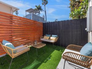 eine Terrasse mit 2 Stühlen, einem Tisch und einem Zaun in der Unterkunft Beach Bungalow Perfection - Private Patios, BBQ walk2beach & Pet Friendly! in San Diego