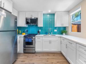 a kitchen with white cabinets and a stainless steel refrigerator at Beach Bungalow Perfection - Private Patios, BBQ walk2beach & Pet Friendly! in San Diego