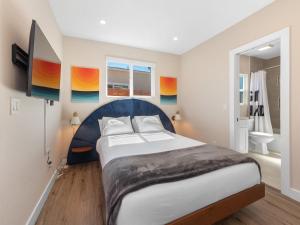 a bedroom with a large bed and a bathroom at Beach Bungalow Perfection - Private Patios, BBQ walk2beach & Pet Friendly! in San Diego