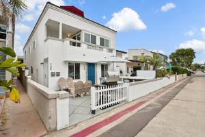 ein weißes Haus mit einem weißen Zaun auf einer Straße in der Unterkunft Beach Perfection - Ocean Views, Parking, Pet Friendly & Steps2Sand in San Diego