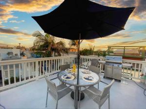 a table and chairs on a balcony with an umbrella at Bay View Paradise - Rooftop Deck, Off-Street Parking, King Suite, WasherDryer & Bay Views! in San Diego