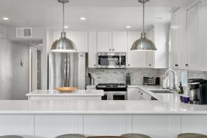 una cocina blanca con armarios blancos y electrodomésticos de acero inoxidable en Stunning Beach Home with Fireplace, Fast WiFi, Grill & Outdoor Seating! en San Diego