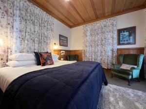 a bedroom with a bed and a chair and curtains at Riverhead Villa in Horoeke