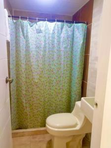 een badkamer met een toilet en een douchegordijn bij Mountain Lodge La Margarita in Quebradanegra