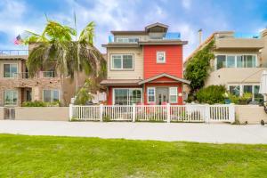 a red house with a white fence in front of a yard at Bayfront Paradise- Bay Views & Boardwalk Patio in San Diego