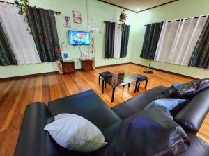 sala de estar con sofá de cuero negro y mesa en 3B Cozy home, en Mauban