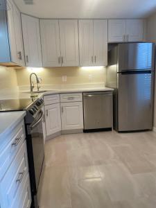 a kitchen with white cabinets and a stainless steel refrigerator at Coastal Townhome in Jupiter 1 mile to beach! in Jupiter