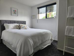 a white bedroom with a bed and a window at Cedar House in Gisborne