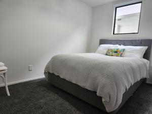 a white bedroom with a bed with a window at Cedar House in Gisborne