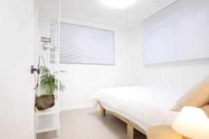 biała sypialnia z łóżkiem i oknem w obiekcie Apartment_Trust w Seulu