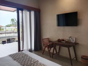 a hotel room with a desk and a television on the wall at FULLMOON CANGGU Nelayan in Canggu