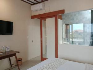 a bedroom with a bed and a desk and a window at FULLMOON CANGGU Nelayan in Canggu