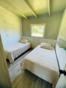 two beds in a room with a window at Casa en Lago Ranco in Ignao