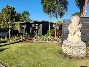 kamienny posąg siedzący na środku podwórza w obiekcie Cedar House w mieście Gisborne