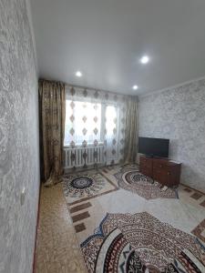 a living room with a television and a window at 408 квартал in Semey