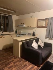 ein Wohnzimmer mit einem Sofa vor einer Küche in der Unterkunft The Garden Cottage Pet Friendly in Renmark