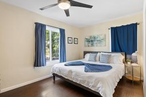 Schlafzimmer mit einem Bett mit blauen Vorhängen und einem Deckenventilator in der Unterkunft Riviera Bay View Dream - Private patio with bay view and parking in San Diego