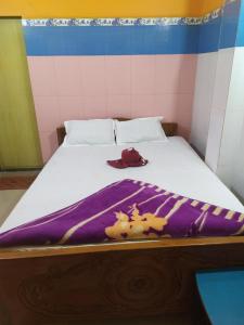 a bed with a purple blanket and a hat on it at PAYEL LODGE in Digha