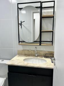 a bathroom with a sink and a mirror at Apartamento perfeito em bairro nobre por insta @thiagojacomo in Goiânia