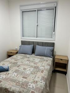 um quarto com uma cama com almofadas azuis e uma janela em Apartamento perfeito em bairro nobre por insta @thiagojacomo em Goiânia