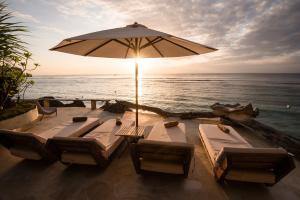 a table with chairs and an umbrella on the beach at Rock'n Reef in Uluwatu