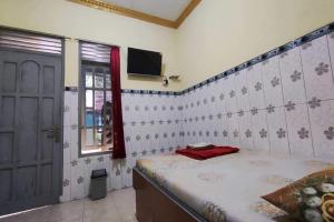 - une chambre avec un lit, une fenêtre et une télévision dans l'établissement OYO 93396 Pondok Wisata Sri Mulyo, à Yogyakarta