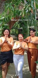 Tres mujeres en camisas anaranjadas que realizan una aplicación de aplicaciónorativorativorativa en Mango Moon, en Pemuteran