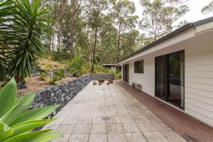 Casa con pared de piedra y patio en Nordhaus, en Smiths Lake