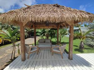 un parasol et des chaises en paille sur une terrasse en bois dans l'établissement Charmante villa de vacances à Moorea, à Afareaitu