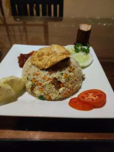 a white plate with a sandwich with rice and a tomato at Jaana Guest in Sigiriya
