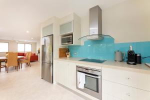 uma cozinha com armários brancos e uma parede azul em Lorikeet 1, 66 Underwood Rd, Forster em Forster